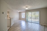 Located at Wildwood Lakes Boulevard in Naples, Florida, this single-floor, 2-bedroom, 2-bathroom home offers a clean, modern layout designed for comfortable living. Light wood-style flooring flows throughout, complementing the neutral warm-gray walls and textured ceilings that lend a consistent, cohesive aesthetic across every room. The welcoming entrance hallway features louvered closet doors and recessed lighting, leading naturally into the open living area. The living room is bright and airy, highlighted by large sliding glass doors dressed with vertical blinds that open to an outdoor view of lush greenery, allowing generous natural light to fill the space. The kitchen is well-appointed with white shaker cabinetry, quartz-style countertops, and a full suite of stainless steel Whirlpool appliances, including a refrigerator, range, and over-the-range microwave, set beneath a tray ceiling detail. Both bedrooms are generously proportioned, each featuring louvered closet doors and windows with outdoor views. The primary bedroom offers a notably spacious footprint. The bathrooms are finished in crisp, clean white tones, with one featuring a full tub-shower combination. A dedicated laundry area houses a full-size Whirlpool washer and dryer, adding everyday convenience to this well-designed Naples residence.