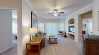 Located at 19411 Via del Mar in Tampa, FL, this single-floor residence offers a well-designed layout with thoughtful finishes throughout. The living room is a welcoming focal point, featuring crown molding, plush carpeting, a ceiling fan, and large sliding glass doors dressed with vertical blinds that invite natural light. A built-in arched niche provides stylish display space alongside a dedicated media area. The open sightline connects the living room directly to the kitchen, enhancing the sense of space and flow. The kitchen is efficiently designed with white shaker-style cabinetry, dark granite-style countertops, a double basin sink, and a full suite of stainless steel appliances including a refrigerator, range, dishwasher, and microwave. Light wood-look flooring grounds the kitchen with a clean, modern aesthetic. The primary bedroom is generously sized with plush carpeting, a ceiling fan, ample natural light, and closet space, while the second bedroom offers similar comfort and a dedicated closet. Both bathrooms are well-appointed, featuring tub-shower combinations and clean, light-toned finishes, with one bathroom showcasing large-format tile flooring and a granite-topped vanity, adding a refined touch to the overall interior.