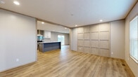 This single-story, 4-bedroom, 2-bathroom home offers a thoughtfully designed layout with a cohesive modern aesthetic throughout. Light-toned luxury vinyl plank flooring flows seamlessly across all rooms, creating a bright and unified look.

The open-concept kitchen and living area serves as the heart of the home. The kitchen is outfitted with crisp white shaker-style cabinetry, a bold navy-blue center island with a white countertop and sink, stainless steel appliances including a refrigerator and range, and a sleek wall-mounted range hood with a tiled backsplash. Recessed lighting illuminates the space, while a sliding glass door in the living area connects to an outdoor deck with exterior views.

A decorative accent wall featuring a grid of light wood paneling adds a distinctive architectural element to the main living space. The front entry area is bright and welcoming, with two large windows allowing ample natural light to fill the room.

The four bedrooms are well-proportioned and finished with the same consistent flooring, neutral wall paneling, and individual windows. The primary bedroom includes a sliding glass door to the deck.

Both bathrooms are cleanly finished. The primary bath features a long double-sink vanity with gray cabinetry, white countertops, and tile accents, while the secondary bath includes a full soaking tub-shower combo with white surround panels.