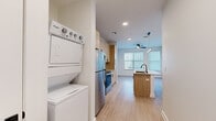 Located at 440 N Monroe St in Tallahassee, FL, this one-bedroom, one-bathroom unit offers a well-designed layout that maximizes every square foot of its compact footprint. The open-concept living and kitchen area is anchored by a sleek kitchen island with a white quartz countertop and an integrated sink with a matte black faucet, providing both prep space and a casual dining option. The kitchen features light wood-toned cabinetry, a white subway tile backsplash, and a full suite of stainless steel appliances including a refrigerator, electric range, and microwave. Light-toned luxury vinyl plank flooring runs throughout the main living areas, lending a clean, contemporary aesthetic. A dedicated in-unit stacked Whirlpool washer and dryer adds everyday convenience. The bedroom is carpeted for comfort, benefits from natural light through a window with blinds, and includes a ceiling fan. A dedicated closet provides storage. The bathroom features a glass-enclosed walk-in shower with a clean white surround and matte black hardware accents. Recessed lighting and a ceiling fan in the main living area contribute to a bright, modern ambiance throughout this efficiently designed unit.