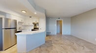 This single-floor, 3-bedroom, 2-bathroom home offers a functional and modern layout designed for comfortable living. The kitchen serves as a central highlight, featuring crisp white cabinetry, a classic subway tile backsplash, stainless steel appliances including a refrigerator, dishwasher, and range, and a white quartz peninsula that opens to the adjacent living area — ideal for both everyday use and entertaining. Large-format stone-look tile flooring flows throughout the main living areas, lending a cohesive and clean aesthetic.

The three bedrooms are well-sized, with the primary bedroom offering generous proportions. Bedrooms feature neutral gray walls, tile flooring, and ceiling fans for added comfort. One bedroom conveniently houses a stacked in-unit washer and dryer alongside a closet with a hanging rod.

The two bathrooms are tastefully finished with wood-look tile floors, white vanities with quartz countertops, and brushed nickel fixtures. One bathroom features a tub-shower combination with floor-to-ceiling gray tile surround, while the second includes a walk-in tiled shower with white subway tile. A dedicated hallway and closet round out the layout, providing practical storage and circulation throughout the home.