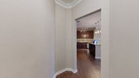This thoughtfully designed one-bedroom, one-bathroom residence offers a comfortable and efficient single-floor layout. The entrance welcomes you with an angled foyer adorned with crown molding detail, leading seamlessly into the open-concept kitchen and living area. The kitchen is a standout feature, boasting rich dark-wood cabinetry, granite-style countertops, stainless steel appliances including a refrigerator, microwave, and dishwasher, plus a center island with pendant lighting — ideal for both cooking and casual dining. Hardwood-style flooring flows throughout the main living areas, enhancing the warm, cohesive aesthetic. The living room is open and airy, benefiting from the kitchen's natural connection. The bedroom offers plush carpeting, a ceiling fan, and a large window that fills the room with natural light and views of the surrounding greenery. The en-suite bathroom features dark wood cabinetry, a single vanity with a large mirror, and hardwood-style flooring. A dedicated in-unit laundry area with a stacked washer and dryer adds everyday convenience. Crown molding and clean neutral tones throughout lend the space a polished, move-in-ready appeal.