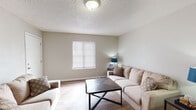 This single-floor, 2-bedroom, 1-bathroom residence in Memphis, TN offers a practical and comfortable layout designed to maximize everyday living. The living room serves as the heart of the home, featuring warm wood-look flooring, neutral-toned walls, and a textured ceiling. A window fitted with blinds allows natural light to fill the space, creating a welcoming atmosphere. The room flows seamlessly into a dedicated dining area, which offers just enough space for a small table and chairs — ideal for casual meals. The kitchen is equipped with warm oak cabinetry, dark countertops, and a double-basin stainless steel sink. A notable feature is the in-unit stacked washer and dryer, neatly integrated within the kitchen cabinetry — a highly practical convenience. Both bedrooms are finished with the same durable wood-look flooring, neutral walls, and windows with blinds that offer natural light and privacy. The full bathroom features a tiled tub-and-shower surround with built-in shelving, providing a clean and functional design. Throughout the unit, consistent flooring, a neutral color palette, and efficient use of space contribute to a cohesive and move-in-ready living environment.