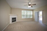 This single-floor residence offers a thoughtfully designed layout that balances comfort and functionality. The spacious living room serves as the heart of the home, featuring plush wall-to-wall carpeting, a ceiling fan with integrated lighting, a classic fireplace, and large windows that invite an abundance of natural light. A sliding glass door leads to an outdoor area, further enhancing the sense of openness. Adjacent to the living room, a pass-through breakfast bar connects to the kitchen, creating a seamless flow between spaces.

The galley-style kitchen is outfitted with warm honey-toned wood cabinetry, light stone countertops, and durable ceramic tile flooring. Black appliances — including a refrigerator, dishwasher, and range — provide a clean contrast to the cabinetry, while ample counter and storage space make it a practical and efficient workspace.

The bedroom is generously sized, finished with soft carpeting and a large window fitted with blinds, allowing for flexible light control and a pleasant outdoor view. Neutral warm-toned walls throughout the residence create a calm, cohesive aesthetic.

The bathroom features tile flooring, white cabinetry with overhead storage, a dark-toned countertop with an undermount sink, and a shower-tub combination, providing all essential amenities in a clean, organized layout.