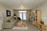 This single-floor residence offers a thoughtfully arranged layout that connects living, dining, and kitchen spaces in a natural, open flow. The living room is a comfortable, well-lit area featuring plush carpeting, a ceiling fan, and French doors that invite natural light from outside. The space accommodates both relaxed seating and an entertainment setup, with room for a dining area nearby.

The galley-style kitchen is efficiently designed with white cabinetry, warm countertops, tile flooring, and a full suite of appliances including a refrigerator, electric range, and built-in microwave. Ample counter and storage space make it highly functional.

Two bedrooms provide restful retreats, each carpeted and equipped with ceiling fans, sliding-door closets, and windows for natural light. One bedroom offers additional flexibility, currently configured as a home office.

Two bathrooms serve the residence, each featuring tile flooring, white cabinetry with warm countertops, and enclosed shower areas — one with a walk-in shower and one with a shower-tub combination. Both are clean and practical in their design.

Throughout, the residence maintains a neutral, warm color palette with consistent finishes, creating a cohesive and inviting atmosphere well-suited for comfortable everyday living.