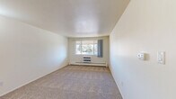 Located at 4920 Thunderbird Cir in Boulder, CO, this two-bedroom, one-bathroom unit offers a practical and well-organized single-floor layout. The spacious primary bedroom is notably generous in size, featuring plush carpeting, a wide window that frames views of mature trees, and a wall-mounted HVAC unit alongside baseboard heating for year-round comfort. A sliding-door closet and an adjacent open shelving closet provide ample storage. The second bedroom, also carpeted, is brightened by a window overlooking greenery and includes its own baseboard heater. The kitchen features warm wood-toned cabinetry, white countertops, a double stainless steel sink, and wood-look vinyl flooring, offering a clean and functional cooking space. The bathroom includes a full tub-shower combo with white tile surround and wood-look flooring. Two hallways connect the rooms, contributing to an efficient flow throughout the unit. Neutral wall tones and consistent carpeting throughout the living areas create a cohesive, understated aesthetic. The unit also benefits from its Boulder location, with natural surroundings visible from multiple windows.