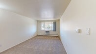 Located at 4920 Thunderbird Cir in Boulder, CO, this two-bedroom, one-bathroom unit offers a practical and well-organized single-floor layout. The spacious primary bedroom is notably generous in size, featuring plush carpeting, a wide window that frames views of mature trees, and a wall-mounted HVAC unit alongside baseboard heating for year-round comfort. A sliding-door closet and an adjacent open shelving closet provide ample storage. The second bedroom, also carpeted, is brightened by a window overlooking greenery and includes its own baseboard heater. The kitchen features warm wood-toned cabinetry, white countertops, a double stainless steel sink, and wood-look vinyl flooring, offering a clean and functional cooking space. The bathroom includes a full tub-shower combo with white tile surround and wood-look flooring. Two hallways connect the rooms, contributing to an efficient flow throughout the unit. Neutral wall tones and consistent carpeting throughout the living areas create a cohesive, understated aesthetic. The unit also benefits from its Boulder location, with natural surroundings visible from multiple windows.