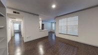 This single-floor residence offers a thoughtfully designed layout that balances open communal spaces with functional private areas. The living and dining area is generously proportioned, featuring rich, dark hardwood-style flooring that extends throughout the entire unit, crisp white walls, and crown molding details that lend an air of refinement. A large window fitted with horizontal blinds allows abundant natural light to fill the space. A pass-through countertop with a sink connects the living area to the kitchen, creating an open, airy flow between the two spaces.

The kitchen is designed for practicality, featuring gray cabinetry, white countertops, a dark tile backsplash, and a full suite of black appliances including a refrigerator, range, microwave, and dishwasher. A dedicated pantry or utility closet provides additional storage.

A standout feature of the unit is a built-in shelving unit framed by architectural columns, offering both display and storage opportunities. The bedrooms are bright and clean, with ample wall space and the same consistent flooring.

Both bathrooms mirror each other in design, showcasing gray vanity cabinetry with chrome hardware, white countertops, large framed mirrors, and a tub-shower combination with decorative tile accenting.