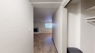 Located at 1251 S Bellaire St in Denver, CO, this two-bedroom, one-bathroom residence offers a practical and comfortable single-floor layout. Wood-look flooring runs throughout the home, creating a cohesive and easy-to-maintain aesthetic. The living room serves as the heart of the space, highlighted by a white-painted brick accent wall and a classic fireplace with a metal screen, adding character and warmth to the room. A window allows natural light to fill the area, enhancing the open feel. The galley-style kitchen features modern white upper cabinetry, dark lower cabinets, light countertops, a stainless steel sink, and stainless steel appliances, offering efficient use of space. The primary bedroom is generously sized and includes two sets of bifold closet doors providing ample storage. The second bedroom is a well-proportioned room with its own closet and a window for natural light. The full bathroom is clean and functional, featuring a tub-shower combination with white tile surround, a vanity with storage, and a window for ventilation. Textured ceilings are present throughout, adding a classic residential touch to this well-laid-out Denver home.