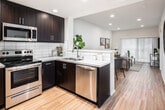 Located at 4662 Lincoln Ave in Cypress, California, this single-story residence offers a well-designed layout with modern finishes throughout. The kitchen is a standout feature, equipped with rich dark espresso cabinetry, crisp white countertops, a classic subway tile backsplash, and a full suite of stainless steel appliances including a refrigerator with ice maker, electric range, over-the-range microwave, and dishwasher. Light wood-tone flooring flows seamlessly throughout the open living and dining area, creating a warm and cohesive atmosphere. The living room is bright and inviting, with vertical blinds allowing natural light to filter in. The dining area accommodates a round table alongside the living space, making the layout highly functional for everyday living and entertaining. The bedroom features multiple windows dressed with horizontal blinds, allowing for ample natural light and a calm, restful environment. Two full bathrooms are finished in a clean, neutral palette, each featuring a tub/shower combination with subway tile surround, modern vanities with dark cabinetry and white countertops, and wood-tone flooring. A dedicated hallway laundry closet houses a stacked washer and dryer unit, adding everyday convenience. Recessed lighting and a skylight further enhance the bright, airy feel of the interior.