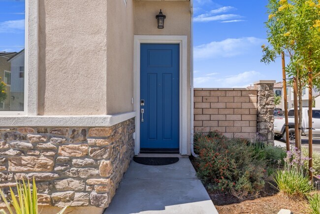 Entrada principal acogedora con una elegante puerta azul, exterior con detalles de piedra y sendero ajardinado - 26549 Brightstone Dr
