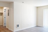 Located at 827 NE 99th Ave in Portland, Oregon, this one-bedroom, one-bathroom unit offers a thoughtfully arranged single-floor layout that makes efficient use of its compact footprint. The living area features light gray wood-look flooring, crisp white walls, and a wall-mounted heater, creating a clean and functional space. A large sliding glass door dressed with vertical blinds fills the room with natural light and opens to a private balcony, adding an outdoor extension to the living space. The kitchen is a standout feature, outfitted with white shaker-style cabinetry extending to the ceiling, stainless steel appliances including a refrigerator, dishwasher, electric range, and built-in microwave, plus a single-basin sink and recessed lighting overhead. The bedroom is carpeted for comfort and includes a wall heater, offering a quiet and cozy retreat. A connecting hallway leads to the full bathroom, which features a white vanity with modern black hardware, a large mirror, and a shower-tub combination with a curtain. The neutral color palette and modern finishes throughout give the space a clean, move-in-ready feel suited for comfortable everyday living.