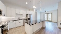 Located at 10221 Whistle Stop Lane in Frisco, TX, this well-appointed one-bedroom, one-bathroom residence offers a thoughtfully designed single-floor layout. The open-concept kitchen and living area serves as the heart of the home, featuring light wood-style flooring, crisp white shaker cabinetry with matte black hardware, and striking dark granite countertops. A central island with a built-in wine rack and pendant lighting above adds both functionality and style. The kitchen is fully equipped with stainless steel appliances, including a French door refrigerator with ice maker, a range, microwave, and dishwasher, complemented by a classic subway tile backsplash. A ceiling fan adds comfort to the living area, which opens to a private balcony, allowing natural light to flow through. The bedroom is a calm retreat with soft carpet flooring, multiple windows with exterior views, and generous natural light. The bathroom features light wood-look tile flooring, a soaking tub with tiled surround, and a white vanity with dark granite countertop. Additional conveniences include a dedicated laundry area, utility room, and a closet for ample storage.