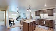 Located in Forest Lake, Minnesota, this thoughtfully designed 2-bedroom, 2-bathroom residence offers a comfortable and functional single-floor layout. The open-concept kitchen and living area serves as the heart of the home, featuring rich dark-stained cabinetry, granite-style countertops, stainless steel appliances, and a central kitchen island with bar seating and a stylish pendant chandelier overhead. Light wood-look flooring flows throughout the main living areas, complementing the bright, airy atmosphere. Large sliding glass doors in the living room invite abundant natural light and provide access to an outdoor area with pleasant views. The living space is generously proportioned and anchored by a ceiling fan for added comfort. Both bedrooms are carpeted and feature windows that bring in natural light, with the spacious primary bedroom offering a serene retreat complete with a closet. The two bathrooms are finished with wood-toned vanities, light countertops, and wood-look flooring. A dedicated in-unit laundry room with a full-size washer and dryer adds everyday convenience. Two closets provide ample storage throughout the residence. The overall ambiance is warm and inviting, with consistent, modern finishes that create a cohesive and comfortable living environment.