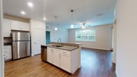 This single-floor residence offers a thoughtfully designed open-concept layout that seamlessly connects the kitchen, dining, and living areas. The kitchen serves as the centerpiece of the space, featuring a large island with a granite countertop, an undermount sink, and pendant lighting overhead. White shaker-style cabinetry provides ample storage, while a full suite of stainless steel appliances — including a refrigerator, range, microwave, and dishwasher — delivers modern functionality. Hardwood-style flooring flows throughout the main living areas, adding warmth and continuity to the design.

The living area is bright and open, benefiting from a large window that invites natural light and offers views of the surrounding greenery. A ceiling fan adds comfort, and a door provides convenient access to an outdoor area. The bedrooms are carpeted for added comfort, with one featuring a walk-in closet and direct access to a private bathroom. The bathrooms are finished with granite-topped vanities, tile-surround tub-shower combinations, and hardwood-style flooring. A dedicated laundry area is also accessible from within the residence. Clean white walls and consistent finishes throughout create a cohesive, move-in-ready environment.