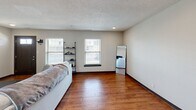 Located at 1600 Kityhawk Dr in Columbia, MO, this two-story, two-bedroom, one-bathroom unit offers a well-organized layout split evenly across two floors. The main level welcomes you through a bold dark front door into a bright living room featuring warm hardwood flooring, a textured ceiling, and multiple windows that allow natural light to fill the space. The adjacent kitchen is well-appointed with rich wood cabinetry, granite countertops, a mosaic tile backsplash, stainless steel appliances, and matching hardwood flooring, creating a cohesive and functional cooking environment. The bathroom on this level includes a vanity with wood cabinetry and a full tub-shower combo. A dedicated laundry room houses a full-size washer and dryer, adding everyday convenience. Upstairs, the layout includes two carpeted bedrooms with windows offering neighborhood and green space views, along with a versatile office equipped with a ceiling fan. The primary bedroom provides a comfortable, quiet retreat. Outside, the property is surrounded by lush, manicured green lawns shaded by mature trees, with a patio area and views of the open, park-like community grounds — offering a peaceful and scenic outdoor setting.