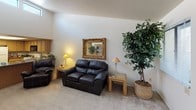 This single-floor residence offers a thoughtfully arranged layout with distinct living spaces connected by an open, flowing floor plan. The living room provides a comfortable and inviting atmosphere, featuring plush carpeting, warm neutral walls, and a decorative gold-framed mirror as a focal point above the seating area. Natural light filters in through windows dressed with vertical blinds, enhancing the bright and airy feel throughout.

The dining area stands out with an elegant tray ceiling fitted with a ceiling fan and light fixture, adding architectural interest to the space. The kitchen is well-equipped with ample oak cabinetry, dark granite-style countertops, and full appliances including a range, over-the-range microwave, and refrigerator.

The residence includes multiple bedrooms, each carpeted and generously sized. The primary bedroom features a walk-in closet and direct access to a bathroom with a granite-style vanity countertop. A secondary bedroom benefits from a large window that allows abundant natural light. Both bathrooms are functional, with one offering a sliding glass door shower enclosure and granite-style countertops throughout. The overall ambiance is warm, neutral, and residential in character.