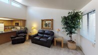 This single-floor residence offers a thoughtfully arranged layout with distinct living spaces connected by an open, flowing floor plan. The living room provides a comfortable and inviting atmosphere, featuring plush carpeting, warm neutral walls, and a decorative gold-framed mirror as a focal point above the seating area. Natural light filters in through windows dressed with vertical blinds, enhancing the bright and airy feel throughout.

The dining area stands out with an elegant tray ceiling fitted with a ceiling fan and light fixture, adding architectural interest to the space. The kitchen is well-equipped with ample oak cabinetry, dark granite-style countertops, and full appliances including a range, over-the-range microwave, and refrigerator.

The residence includes multiple bedrooms, each carpeted and generously sized. The primary bedroom features a walk-in closet and direct access to a bathroom with a granite-style vanity countertop. A secondary bedroom benefits from a large window that allows abundant natural light. Both bathrooms are functional, with one offering a sliding glass door shower enclosure and granite-style countertops throughout. The overall ambiance is warm, neutral, and residential in character.