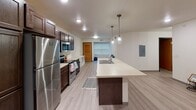 Located at 1010 Vine St in La Crosse, Wisconsin, this single-floor unit offers a clean, modern design with consistent finishes throughout. The kitchen serves as a central highlight, featuring rich dark-stained cabinetry, stainless steel appliances including a refrigerator, microwave, and electric range, as well as light countertops and a large island with an integrated sink. Industrial-style pendant lighting adds a contemporary touch, while light wood-look flooring extends seamlessly into the open living area. Multiple bedrooms are thoughtfully designed, each featuring ceiling fans, natural light through wide windows fitted with horizontal blinds, and built-in desks or shelving for added functionality. The light-toned walls and durable flooring create a bright and cohesive atmosphere in each room. The bathrooms are finished with light wood-look flooring, full tub-shower combinations with curtain rods, and clean white surrounds. One bathroom features a vanity area with dark cabinetry that mirrors the kitchen aesthetic, topped with a mirrored medicine cabinet and industrial-style light fixtures. Ample storage cabinetry completes the space. Overall, this unit presents a practical and modern layout suited for comfortable everyday living.