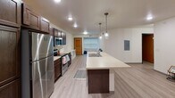 Located at 1010 Vine St in La Crosse, Wisconsin, this single-floor unit offers a clean, modern design with consistent finishes throughout. The kitchen serves as a central highlight, featuring rich dark-stained cabinetry, stainless steel appliances including a refrigerator, microwave, and electric range, as well as light countertops and a large island with an integrated sink. Industrial-style pendant lighting adds a contemporary touch, while light wood-look flooring extends seamlessly into the open living area. Multiple bedrooms are thoughtfully designed, each featuring ceiling fans, natural light through wide windows fitted with horizontal blinds, and built-in desks or shelving for added functionality. The light-toned walls and durable flooring create a bright and cohesive atmosphere in each room. The bathrooms are finished with light wood-look flooring, full tub-shower combinations with curtain rods, and clean white surrounds. One bathroom features a vanity area with dark cabinetry that mirrors the kitchen aesthetic, topped with a mirrored medicine cabinet and industrial-style light fixtures. Ample storage cabinetry completes the space. Overall, this unit presents a practical and modern layout suited for comfortable everyday living.