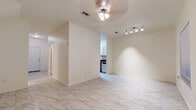This two-story home offers a clean, functional layout spread across two well-defined levels. The main floor is anchored by an open living and dining area dressed in large-format marble-look tile flooring, which lends a bright, airy feel throughout. Ceiling fans with light fixtures provide both comfort and illumination, while a track lighting system adds a modern accent. The galley-style kitchen is efficiently designed, featuring white shaker cabinetry, dark granite-look countertops, a stainless steel sink, and black appliances including a gas range and refrigerator. A window at the end of the kitchen allows natural light to filter in. A convenient half bathroom on the main level includes white cabinetry with a dark countertop vanity and matching marble-look tile flooring. The staircase leads to the upper level, where carpeted bedrooms offer a softer, more relaxed atmosphere. The primary bedroom is generously sized with dual windows overlooking lush greenery, providing a tranquil, nature-filled backdrop. Full bathrooms on the upper level are finished with white tile surround tub-shower combinations, marble-look tile floors, and white vanities with dark countertops, maintaining a consistent and cohesive aesthetic throughout the home.