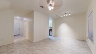This two-story home offers a clean, functional layout spread across two well-defined levels. The main floor is anchored by an open living and dining area dressed in large-format marble-look tile flooring, which lends a bright, airy feel throughout. Ceiling fans with light fixtures provide both comfort and illumination, while a track lighting system adds a modern accent. The galley-style kitchen is efficiently designed, featuring white shaker cabinetry, dark granite-look countertops, a stainless steel sink, and black appliances including a gas range and refrigerator. A window at the end of the kitchen allows natural light to filter in. A convenient half bathroom on the main level includes white cabinetry with a dark countertop vanity and matching marble-look tile flooring. The staircase leads to the upper level, where carpeted bedrooms offer a softer, more relaxed atmosphere. The primary bedroom is generously sized with dual windows overlooking lush greenery, providing a tranquil, nature-filled backdrop. Full bathrooms on the upper level are finished with white tile surround tub-shower combinations, marble-look tile floors, and white vanities with dark countertops, maintaining a consistent and cohesive aesthetic throughout the home.