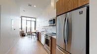 Located on Wilshire Boulevard in the heart of Los Angeles, this modern residential unit offers a thoughtfully designed open-concept layout with clean lines and contemporary finishes throughout. Light wood flooring flows seamlessly across the entire space, lending warmth and cohesion to every room.

The kitchen is a standout feature, outfitted with a full suite of stainless steel appliances including a French door refrigerator, electric range, built-in microwave, and dishwasher. Two-tone cabinetry — combining white upper cabinets with warm wood lower panels — is complemented by a white quartz countertop and a marble-style tile backsplash, creating a refined yet functional cooking environment.

The open living and dining area is bathed in natural light from floor-to-ceiling windows, which also frame expansive views of the Los Angeles skyline. The bright, airy bedroom benefits from the same generous glazing, offering a serene retreat with ample natural light and city views.

The bathroom features floor-to-ceiling white subway tile in the tub and shower surround, a wood-accented vanity with a white countertop, and clean, minimalist chrome fixtures. Throughout the unit, soaring ceilings amplify the sense of space, making this a compelling residence in one of LA's most vibrant corridors.