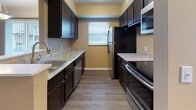 Located at 175 Cousins Dr in Carlisle, Ohio, this single-floor residence offers a thoughtfully designed layout that balances comfort and functionality. The living area is warm and welcoming, featuring neutral-toned walls, plush wall-to-wall carpeting, and a large sliding door with vertical blinds that allows natural light to flow in. A pendant light fixture adds a subtle decorative touch overhead.

The kitchen is designed for practicality, featuring rich dark cabinetry that contrasts beautifully with light granite-style countertops. Wood-look flooring runs throughout, and the space is well-equipped with stainless steel and black appliances, including a refrigerator, electric range, microwave, and dishwasher. A window above the counter brings in natural light, and a pass-through peninsula connects the kitchen to the living area, enhancing the open feel of the floor plan.

The bedrooms are carpeted and finished in warm neutral tones. One bedroom benefits from dual windows on adjacent walls, filling the room with abundant natural light and offering views of the surrounding area.

The bathroom is clean and well-appointed, featuring a white vanity with a mirrored medicine cabinet, brushed nickel fixtures, and a full tub-shower combination. Dark hardwood-style flooring anchors the space with a modern contrast to the light fixtures and cabinetry.