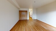 Located at 945 NW Naito Pkwy in Portland's vibrant Pearl District/Old Town waterfront corridor, this efficiently designed single-floor unit offers a well-organized layout that makes smart use of every square foot. Light wood-style flooring runs throughout the main living areas, lending warmth and visual continuity to the space.

The kitchen is positioned along one side of the unit and features white cabinetry with warm wood trim, a white electric range, a full-size refrigerator, and a countertop sink — providing all the essentials in a compact, functional arrangement. The kitchen opens directly into the main living area, which is bathed in natural light from a window with exterior views, creating a bright and open atmosphere.

The main living area is clean and versatile, with neutral white walls, wood-trimmed accents, and a door leading to a private balcony — a notable feature that extends the living space outdoors. Two closets provide practical storage solutions within the unit.

The bathroom is neatly appointed with a single-sink vanity featuring wood-trimmed cabinetry, a large wall mirror, and a shower/tub combination, maintaining the consistent neutral and warm aesthetic found throughout the unit. Overall, the space offers a straightforward, functional design well-suited to urban living in one of Portland's most accessible neighborhoods.