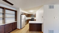 Located at 2725 N University Dr in Waukesha, WI, this 2-bedroom, 2-bathroom residence offers a practical and well-designed single-floor layout. The kitchen is a standout feature, showcasing rich dark-wood cabinetry, stainless steel appliances including a refrigerator, range, microwave, and dishwasher, complemented by light quartz countertops and a peninsula that provides additional workspace and casual seating. Light hardwood-style flooring runs throughout the kitchen and living areas, lending a warm, cohesive feel. The spacious living room benefits from a sliding glass door that invites natural light and provides outdoor access. Both bedrooms are carpeted for added comfort; the primary bedroom offers a generous footprint, while the second bedroom features a window with views of the surrounding area. The two bathrooms are finished with tile flooring and warm wood cabinetry. One bathroom includes a tub-shower combination with sliding glass doors framed by an arched alcove, while the second features a walk-in glass shower. Open shelving built into a nook near the kitchen adds a decorative and functional touch. The overall design is clean, neutral, and move-in ready.