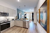 Located at 1950 Winrock Blvd in Houston, TX, this thoughtfully designed one-bedroom, one-bathroom residence offers an efficient and stylish single-floor layout. Light wood-tone flooring flows throughout, providing a warm, cohesive foundation across every room.

The open-concept kitchen, dining, and living area forms the heart of the space. The kitchen features white shaker cabinetry, dark countertops, a stainless steel dishwasher, a tiled backsplash, and a peninsula with pendant lighting overhead. This flows naturally into the dining and living areas, where a striking teal accent wall adds depth and character. Large windows allow natural light to fill the living room.

The bedroom continues the teal accent wall motif and benefits from a generous window. Three closets — including a spacious walk-in — provide ample storage with built-in shelving and hanging rods. The bathroom is well-proportioned, offering a gray vanity with stone countertops, open shelving, and a shower-tub combination. A dedicated laundry area and a private patio round out the functional offerings of this residence. Recessed lighting and clean white walls throughout contribute to a bright, modern ambiance.