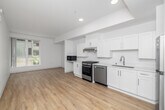Located at 1999 W 3rd St in Los Angeles, CA, this thoughtfully designed one-bedroom, one-bathroom unit offers a clean, modern aesthetic throughout. Light wood-look flooring runs seamlessly across the entire space, complementing the crisp white walls and creating a bright, cohesive atmosphere.

The open-plan kitchen and living area forms the heart of the unit. The well-equipped kitchen features white shaker-style cabinetry, light countertops, stainless steel appliances including a gas range, dishwasher, and refrigerator, plus a built-in microwave. A large window in the living area fills the space with natural light and provides views of the surrounding neighborhood.

The bedroom is a comfortable, well-proportioned retreat with a tall vertical window framing outdoor views of palm trees and greenery. Two closets provide generous storage for the space. A hallway connects the main living areas to the bedroom and bathroom.

The bathroom is designed with accessibility in mind, featuring grab bars, a white vanity with ample cabinet storage, and the same warm wood-look flooring found throughout the unit. Recessed lighting and a neutral color palette give the entire residence a clean, move-in-ready feel suited for modern urban living in the heart of Los Angeles.