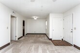 Located at 101–111 Castle Dr in Dothan, Alabama, this single-story unit offers a functional and straightforward layout across several well-defined spaces. The living area is generously sized, featuring neutral-toned carpet, dark baseboards, and a ceiling fan with integrated lighting. A set of vertical-blind-covered sliding glass doors provides access to an outdoor area while allowing natural light to fill the room.

The kitchen is a standout feature, equipped with rich dark wood cabinetry, light granite-style countertops, a mosaic tile backsplash, a black electric range, and hardwood-style flooring — offering a practical and visually appealing workspace.

The bedrooms are carpeted and bright, each fitted with ceiling fans and ample wall space. At least one bedroom includes a walk-in closet with built-in shelving, adding useful storage. Additional rooms provide flexible space with similar neutral finishes and ceiling fan lighting.

The bathroom features a full tub-shower combination with chrome fixtures and hardwood-style flooring, maintaining a clean, utilitarian aesthetic consistent throughout the unit. Dark baseboards and light walls create a cohesive visual theme across all rooms.