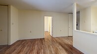 Located at 600 Sycamore Terrace in Shelbyville, Kentucky, this one-bedroom, one-bathroom unit offers a practical and well-organized layout across a single floor. Wood-look flooring flows consistently throughout the main living areas, lending a cohesive and clean aesthetic to the space.

The living room provides an open, uncluttered area with neutral cream-toned walls and access to the kitchen via a convenient pass-through window, enhancing the sense of openness between the two spaces. The kitchen features warm oak cabinetry, dark laminate countertops, and white appliances including a range and refrigerator, all set atop matching wood-look flooring.

The bedroom is a comfortable, well-proportioned room with natural light provided by a window with blinds. A baseboard heating unit and a wall-mounted HVAC unit ensure year-round comfort. The room also benefits from good closet access, with four closets distributed throughout the unit offering generous storage.

The bathroom includes a wall-mounted sink, a mirrored medicine cabinet with overhead lighting, a full tub and shower combination with grab bar, and tile flooring. A dedicated utility room adds further functionality to the layout. Overall, the unit presents a straightforward, practical living environment in a residential Shelbyville community.