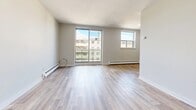 This well-appointed one-bedroom, one-bathroom unit at 23 Lynnwood Dr in Brantford, Ontario offers a practical and comfortable single-floor layout. Light hardwood-style flooring runs throughout the living areas and bedroom, giving the space a clean, cohesive feel. The living room is generously sized, featuring large sliding doors and an additional window that flood the room with natural light and offer views of the surrounding neighbourhood. Baseboard heating is present throughout, ensuring year-round comfort. The galley-style kitchen is efficiently designed with rich warm-toned cabinetry, granite-look countertops, a mosaic tile backsplash, and stainless steel appliances including a range and refrigerator. Light ceramic tile flooring completes the kitchen's functional aesthetic. The bedroom is a comfortable size, featuring dual closets for ample storage, a window with natural light, and the same warm hardwood-style flooring found throughout. The bathroom is clean and simply finished, featuring full-height white tile surrounding a soaker bathtub, with light tile flooring tying the room together. The overall design is neutral and move-in ready, making this unit a practical choice in a residential Brantford setting.