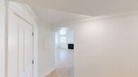This well-designed single-floor residence offers a clean, light-filled interior characterized by a consistent white color palette, crown molding throughout, and a thoughtful layout. The living area is a standout space, anchored by a classic fireplace with a white surround and framed by multiple windows that invite abundant natural light. A graceful arched entryway connects the hallway to the living room, adding an elegant architectural detail to the open flow of the space. Light hardwood flooring runs throughout the main living and common areas, lending warmth and continuity.

The kitchen is well-equipped and functional, featuring granite countertops, white shaker-style cabinetry, a stainless steel appliance suite including a refrigerator, range, and over-the-range microwave, and a double-basin sink. A peninsula provides additional workspace and defines the kitchen's boundary with the adjoining living area.

The bedrooms offer plush neutral carpeting, crown molding, and windows with outdoor views of surrounding greenery. Closet access is conveniently located within each room. The bathrooms are finished with granite-topped vanities, white cabinetry, tile flooring, and a soaking tub with mosaic tile surround in one, while another features a large window that fills the space with natural light.
