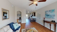 This well-appointed single-floor residence at Wyndamere offers a thoughtfully designed open-concept layout that seamlessly connects the living, dining, and kitchen areas. Rich hardwood flooring runs throughout the main living spaces, while a ceiling fan overhead adds both style and comfort. An elegant arched alcove adds architectural character to the living room, which flows naturally toward a private outdoor area visible through large windows and a glass door.

The kitchen is a standout feature, outfitted with dark espresso cabinetry, marble-style countertops, black appliances, and a peninsula with bar seating illuminated by pendant lighting — ideal for casual dining or entertaining. A dedicated galley-style workspace provides ample prep and storage space.

The bedrooms are generously sized, each featuring plush wall-to-wall carpeting and windows that invite natural light. The primary bedroom offers comfortable proportions and neutral tones that create a calm, restful atmosphere. Additional bedrooms are equally well-suited for guests or flexible use.

Two full bathrooms serve the home, both featuring dark wood vanities, tile flooring, and tub-shower combinations. Clean, neutral finishes throughout maintain a cohesive and inviting aesthetic across every room in the home.