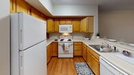 Located at 9 Winthrop St in Rochester's vibrant 14607 neighborhood, this single-floor unit offers a well-organized layout designed for comfortable everyday living. The kitchen is a functional U-shaped space outfitted with warm honey-toned wood cabinetry offering generous upper and lower storage, light-colored countertops, a full suite of white appliances including a refrigerator, electric range with overhead microwave, and dishwasher, and durable hardwood-style flooring. A peninsula counter provides additional workspace and a natural transition into the adjacent living area. The living room is a generously proportioned space with plush carpeting, neutral walls, a ceiling fan with integrated lighting, and a set of glass French doors that open onto a private balcony with outdoor views. The bedroom areas feature soft carpeting, neutral gray-toned walls, and six-panel white doors, with one bedroom offering a window that brings in natural light. The full bathroom includes tile flooring, a wood-finish vanity with an integrated sink, a lighted mirror, and a full-size soaking tub with a shower surround. Throughout the unit, clean white trim and a consistent neutral palette create a cohesive, move-in-ready ambiance.