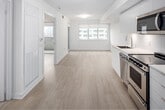 Located at 44 Lillian in Toronto, this one-bedroom, one-bathroom unit offers a well-designed, open-concept layout finished in a clean, contemporary aesthetic. Light hardwood flooring runs throughout the living spaces, complementing the crisp white walls and creating a bright, cohesive atmosphere.

The kitchen is efficiently laid out with floor-to-ceiling white cabinetry, white subway tile backsplash, and a full suite of stainless steel appliances including a refrigerator, electric range, built-in microwave, and dishwasher. A single-basin undermount sink with a modern arc faucet adds a refined touch.

The open living area receives ample natural light through a large window fitted with a roller shade, and sliding glass doors lead to a private balcony with city views. The bedroom is a comfortable size, featuring its own sliding glass door to the balcony, a wide window, and a built-in closet with mirrored sliding doors offering practical storage.

The bathroom is finished in all-white tiling and includes a soaker tub with overhead shower, a wall-mounted vanity with a rectangular mirror, and in-unit laundry facilities. The overall design prioritizes clean lines, functionality, and a light, airy feel throughout.