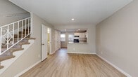 Located at 1719 Eastcrest Dr in Charlotte, NC, this two-story home offers a bright, well-maintained interior with a cohesive, modern aesthetic throughout both floors. The main level welcomes visitors through a front entry door with a fanlight window, opening into a spacious living area finished with light-toned luxury vinyl plank flooring that extends throughout the lower level. A staircase with a metal railing leads to the upper floor. The open layout connects the living space directly to the kitchen, which is outfitted with white shaker-style cabinetry, granite countertops, a peninsular breakfast bar, and black appliances including a range, dishwasher, and refrigerator. Recessed lighting illuminates the kitchen, and a range hood is installed above the stove. Multiple closet doors near the kitchen provide additional storage. The upper level features carpeted bedrooms bathed in natural light from window-fitted walls with blinds, offering a quiet and comfortable retreat. The bathroom is finished with large-format tile flooring and tiled tub surround, accented with a decorative mosaic tile inlay and fitted with brushed nickel fixtures. Neutral warm-gray paint tones are carried consistently throughout the home, contributing to its clean, move-in-ready presentation.