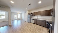 Located at 8575 Merchants Way in Jacksonville, FL, this one-bedroom, one-bathroom unit offers a well-designed single-floor layout that maximizes functionality. The open-concept living, dining, and kitchen area forms the heart of the home, featuring light wood-style flooring, recessed lighting, and a ceiling fan. The kitchen is outfitted with dark walnut-toned cabinetry, granite-style countertops, and a full suite of stainless steel appliances including a refrigerator, range, microwave, and dishwasher. Natural light flows into the living area through windows and a glass patio door, which opens to a private outdoor patio. The bedroom is carpeted for comfort, features a ceiling fan, a window with outdoor views, and connects to a spacious walk-in closet with built-in wire shelving. The bathroom includes a single-sink vanity with matching dark cabinetry, granite-style countertops, a large mirror, and a soaking tub. A dedicated in-unit laundry area adds everyday convenience. Throughout, the unit maintains a clean, modern aesthetic with neutral tones and consistent finishes.