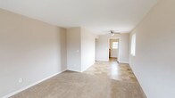 Located at 1804 Belvo Rd in Miamisburg, Ohio, this single-floor home offers a straightforward and functional layout well-suited for comfortable everyday living. The main living area is generously sized, featuring neutral beige walls, soft carpet flooring, and a ceiling fan with integrated lighting. Natural light filters in through multiple windows fitted with blinds, creating a bright and welcoming atmosphere. The space transitions seamlessly into a dining or entry area finished with tile flooring, leading to the kitchen. The kitchen is equipped with warm wood cabinetry, granite-style countertops, a double-basin stainless steel sink, and a door providing direct exterior access with a window for additional natural light. The bedrooms are carpeted and painted in neutral tones, each offering closet storage with sliding or bi-fold doors and windows that bring in natural light. The full bathroom features tile flooring, a combined tub and shower, a toilet, and a dark-toned vanity with storage. A hallway connects the bedrooms and bathroom, with a thermostat and utility access panel visible along the corridor. Throughout the home, clean white trim and understated finishes provide a versatile, move-in ready canvas.