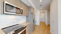 Located at 1933 S Acoma St in Denver, Colorado, this single-floor residence showcases a clean, modern design with thoughtfully selected finishes throughout. The kitchen is a standout feature, outfitted with flat-front light wood cabinetry, light-toned quartz countertops, and a marble-style tile backsplash. Stainless steel appliances — including a French door refrigerator, electric range, and over-the-range microwave — lend a polished, contemporary feel. Recessed lighting illuminates the space efficiently. Light hardwood-style flooring runs continuously through the kitchen, hallway, and living areas, creating a cohesive and warm aesthetic. The hallway connects the kitchen to the remaining rooms in a straightforward, functional layout. The bedroom is bright and open, featuring the same light flooring, crisp white walls, and a ceiling fan with an integrated light fixture. The bathroom is elegantly appointed with full marble-look porcelain tile lining the walk-in shower walls, complemented by a frameless glass door and brushed nickel fixtures, adding a refined touch. Throughout the unit, white walls and recessed lighting contribute to a bright, airy ambiance. The overall design balances modern minimalism with practical livability, making this Denver residence a well-finished and comfortable space.