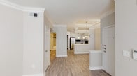 Located at 3225 Woodland Park Dr in Houston, TX, this single-floor residence offers a thoughtfully designed layout with modern finishes throughout. The open-concept kitchen serves as a central highlight, featuring light gray shaker-style cabinetry, white quartz countertops, a stainless steel refrigerator, range, and built-in microwave, all complemented by a stylish mosaic tile backsplash. A peninsula with an undermount sink and pendant lighting above creates a seamless connection between the kitchen and the main living area. Wood-look plank flooring extends throughout the common areas, adding warmth and continuity to the space. Tray ceilings with crown molding detail elevate the architectural character of both the main living area and the bedroom, lending a sense of added height and refinement. The bedroom is carpeted for comfort and features vertical blinds offering privacy and light control. The bathroom is finished with large-format marble-look tile extending floor to ceiling in the tub surround, accented by a dark decorative border, and paired with a white vanity and generous mirror. A pantry closet and efficient hallway layout contribute to the overall functionality of this well-appointed Houston residence.