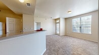 This 2-bedroom, 2-bathroom unit in Maumelle, Arkansas offers a practical and well-organized single-floor layout. The open-concept living and kitchen area serves as the heart of the home, where a peninsula counter with a double sink separates the kitchen from the living space. The kitchen is equipped with warm wood-toned cabinetry, a full suite of white appliances including a range, microwave, refrigerator, and dishwasher, along with track lighting that brightens the workspace. Dark hardwood-style flooring runs through the kitchen and entry areas, adding contrast to the neutral beige walls found throughout. The living room is carpeted and receives natural light through multiple windows, including a front-facing entry door with sidelights. Both bedrooms are carpeted and well-lit by windows offering outdoor views. The primary bedroom features a dedicated walk-in closet outfitted with wire shelving and hanging rods for ample storage. The bathrooms include wood-style flooring, and at least one features a shower-tub combination. A dedicated in-unit laundry area with shelving above the washer adds everyday convenience. Overall, the space presents a clean, functional layout suited for comfortable residential living.