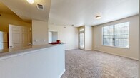 This 2-bedroom, 2-bathroom unit in Maumelle, Arkansas offers a practical and well-organized single-floor layout. The open-concept living and kitchen area serves as the heart of the home, where a peninsula counter with a double sink separates the kitchen from the living space. The kitchen is equipped with warm wood-toned cabinetry, a full suite of white appliances including a range, microwave, refrigerator, and dishwasher, along with track lighting that brightens the workspace. Dark hardwood-style flooring runs through the kitchen and entry areas, adding contrast to the neutral beige walls found throughout. The living room is carpeted and receives natural light through multiple windows, including a front-facing entry door with sidelights. Both bedrooms are carpeted and well-lit by windows offering outdoor views. The primary bedroom features a dedicated walk-in closet outfitted with wire shelving and hanging rods for ample storage. The bathrooms include wood-style flooring, and at least one features a shower-tub combination. A dedicated in-unit laundry area with shelving above the washer adds everyday convenience. Overall, the space presents a clean, functional layout suited for comfortable residential living.