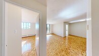 This two-bedroom, one-bathroom unit is laid out on a single floor, offering a practical and efficiently designed living space. Parquet hardwood flooring is a consistent feature throughout the main living areas and both bedrooms, lending warmth and a classic character to the interior. The textured ceiling adds architectural detail to the common areas.

The open living area benefits from a floor-to-ceiling sliding glass door that leads to a balcony, allowing ample natural light and outdoor views of surrounding greenery. Baseboard heating runs along the exterior walls throughout the unit, ensuring consistent climate control.

The spacious primary bedroom features a large window, parquet flooring, and a sliding-door closet providing generous storage. The second bedroom also includes parquet flooring, a window with natural light, and its own closet. Both rooms are bright and functional.

The kitchen is finished with light ceramic tile flooring, a window overlooking the outdoors, built-in cabinetry, and a laminate countertop. The bathroom is fitted with full-height ceramic wall tiles surrounding a soaking bathtub with an overhead shower, complemented by tile flooring in neutral tones. A dedicated entrance completes the layout.
