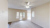 Located at 2900 W Highland St in Chandler, Arizona, this two-bedroom, one-bathroom residence offers a practical and comfortable single-floor layout. The living room serves as the heart of the home, featuring plush carpeting, a textured ceiling, a ceiling fan with light fixture, and a glass-paned door that opens to the outdoors, filling the space with natural light. A pass-through window connects the living area to the kitchen, enhancing the open feel between rooms. The kitchen is equipped with light wood cabinetry, dark countertops, wood-look flooring, and a full-size refrigerator, with a window overlooking the exterior providing additional natural light. An adjacent dining area flows naturally from the kitchen. Both bedrooms are generously proportioned, with the primary bedroom offering especially spacious dimensions. Each bedroom features plush carpeting, a ceiling fan, and a large window with vertical blinds. The well-organized closet includes dual hanging rods and a central built-in shelving unit, maximizing storage capacity. The bathroom features wood-look flooring, a vanity with dark countertops, and a separate compartment housing the shower-tub combination. Neutral warm tones throughout create a cohesive and inviting atmosphere.