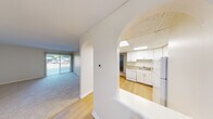 This single-floor residence offers a clean, functional layout designed for comfortable everyday living. The living area is generously sized, featuring soft wall-to-wall carpeting and a sliding glass door that fills the space with natural light and provides views of the outdoors. A graceful arched opening connects the living area to the rest of the unit, adding a subtle architectural detail to the otherwise clean, neutral interior.

The kitchen is well-appointed with white cabinetry, granite-look countertops, and a full suite of white appliances including a range, over-the-range microwave, dishwasher, and refrigerator. A drop-ceiling with a skylight panel brightens the kitchen with additional natural light, while light hardwood-style flooring adds warmth underfoot.

A dedicated dining area adjacent to the living space features light hardwood-style flooring and an elegant pendant light fixture overhead. The bedrooms are carpeted and offer ample space, each equipped with built-in closets featuring bi-fold doors. The bathroom includes a tub-shower combination and a tall built-in shelving unit, providing convenient storage. Throughout the unit, a neutral color palette and consistent finishes create a cohesive and move-in ready environment.