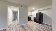Located at 9680 Lexington Ave in De Soto, Kansas, this single-story home offers four bedrooms and two full bathrooms within a practical, well-organized floor plan. The kitchen features white cabinetry, black appliances including an electric range and full-size refrigerator, and a double sink, all set against durable wood-look luxury vinyl plank flooring that also runs through the hallway and bathrooms. A central hallway connects the main living areas to the bedrooms, maintaining a clear and efficient flow throughout the home. The generously sized primary bedroom stands out for its substantial footprint and includes a walk-in style closet with dedicated storage space. The remaining three bedrooms are carpeted for comfort, each offering a window with natural light and sliding or hinged closet doors for ample storage. Both bathrooms are finished with LVP flooring, white vanities with speckled countertops, and one includes a full tub-shower combination. Neutral wall tones and clean white trim are consistent throughout, lending the home a bright, move-in-ready appearance. The overall design is straightforward and functional, making efficient use of the available space across the single floor.
